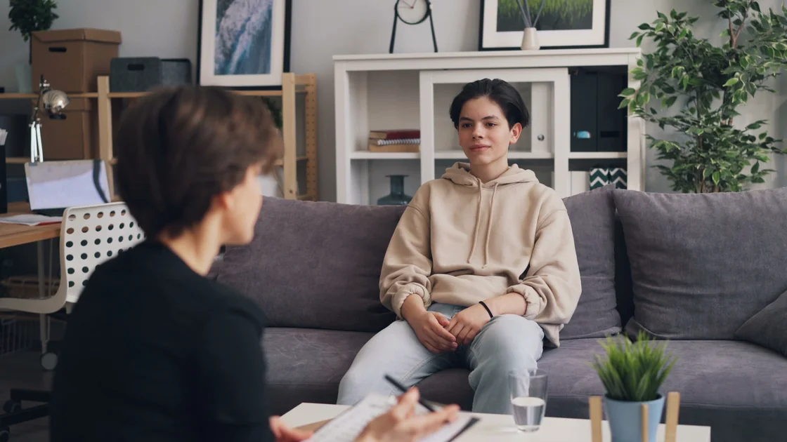 Two people sitting and talking together in a warm, softly lit room.